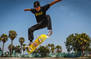 Skateboarder in San Diego, CA using a Wich! Mtn Dew Vibe skateboard. Background is blue skies and palm trees.